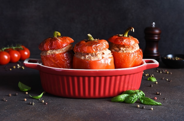 Photo poivre farci. poivrons cuits au four avec du riz et de la viande et du basilic sur un fond de béton foncé.