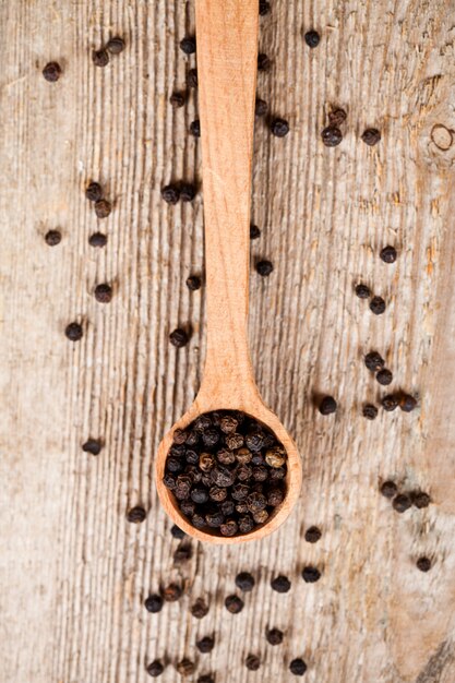 Poivre noir dans une cuillère en bois