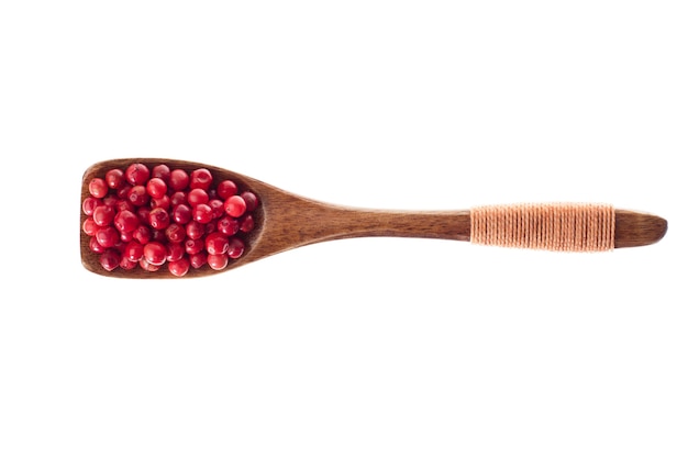 poivre rose aux épices dans une cuillère en bois isolé sur fond blanc, vue de dessus