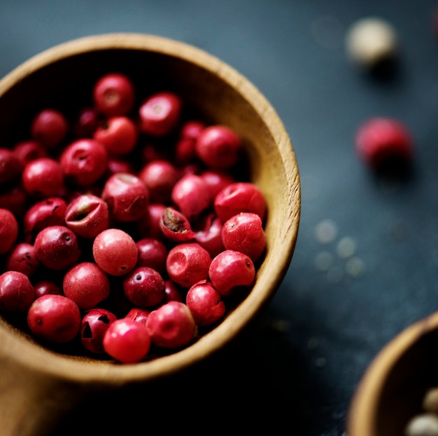 Poivre rose dans une cuillère en bois