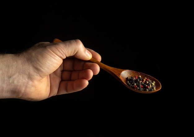 Poivre sec dans une cuillère vintage dans la main du cuisinier avant d'ajouter à la nourriture Espace noir pour la publicité