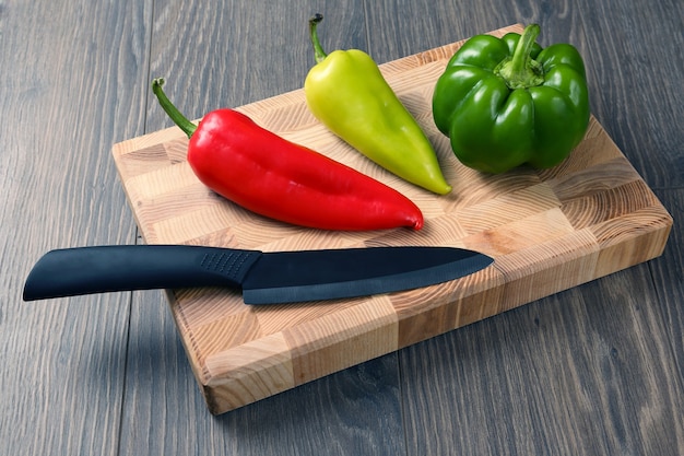 Poivron avec un couteau en céramique sur une planche de bois