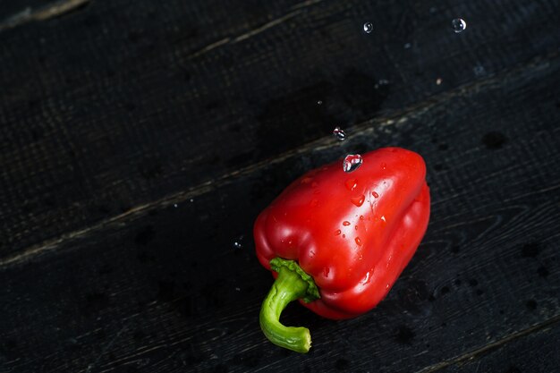 Poivron rouge sur bois noir.