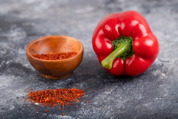 Poivron rouge et bol en bois de piment moulu sur marbre.