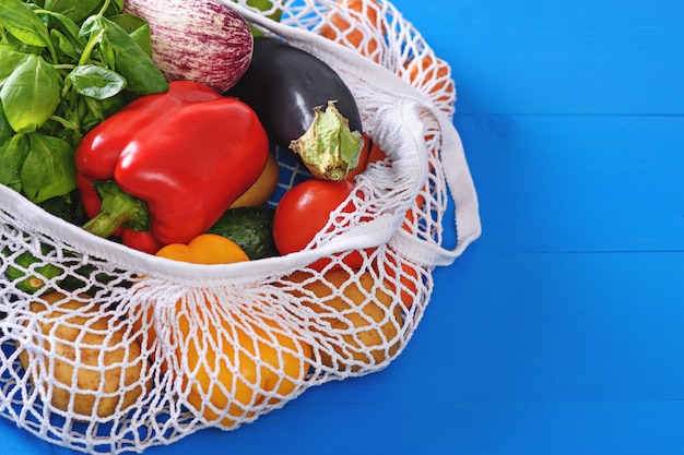 Poivrons, aubergines, épinards, tomates, carottes dans un sac de fil blanc