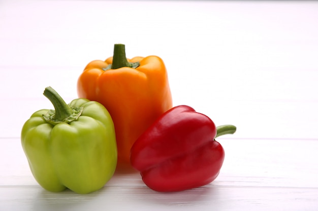 Poivrons colorés sur une table en bois blanc. Paprika coloré sur fond en bois