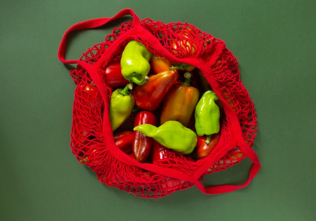 Poivrons frais dans un sac écologique sur fond vert