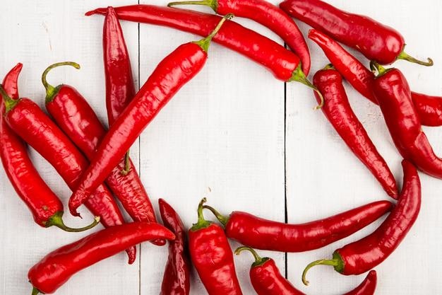 Poivrons pepperoni rouges sur une table en bois blanche