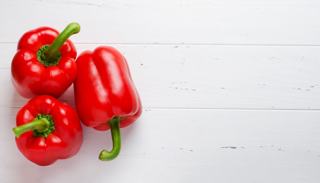 Poivrons rouges sur fond de bois blanc