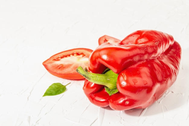 Photo poivrons rouges géants et tomates sur fond blanc. légume sucré, nouvelle récolte, ingrédient frais pour une alimentation saine, gros plan