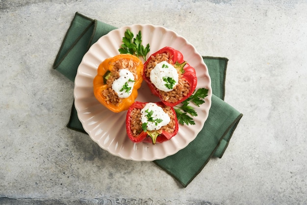 Poivrons rouges et jaunes farcis rôtis avec riz brun au couscous et épeautre avec sauce grecque et huile d'olive sur fond en bois rustique Dîner sain manger Concept de dîner confortable d'automne Vue de dessus