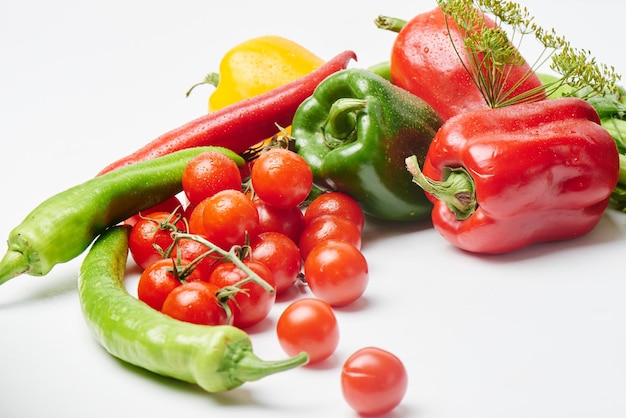 Poivrons, tomates cerises, aubergines et aneth sur fond blanc avec espace de copie. Légumes multicolores frais.