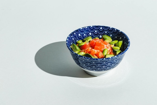 Poke bol avec riz avocat haricots edamame et saumon fumé lumière dure ombre profonde