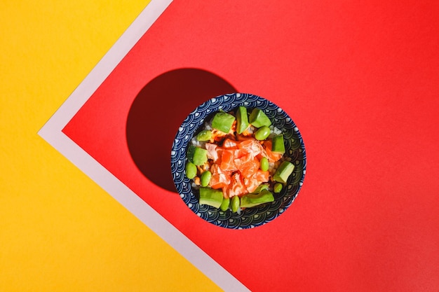 Poke bol avec riz avocat haricots edamame et saumon fumé lumière dure ombre profonde