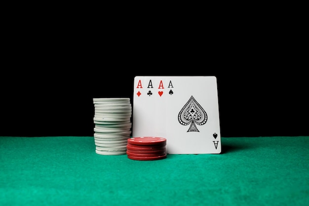 Poker Senior. Quatre cartes à jouer, quatre as et des jetons de poker sur une table de casino verte.