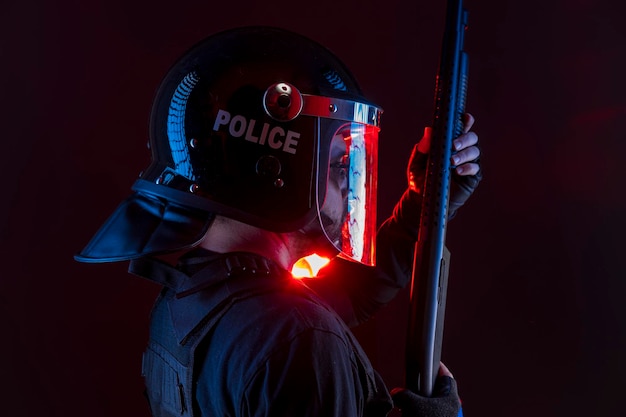 policier avec équipement complet pour anti-émeute, exécuteur de la loi en uniforme de protection prêt pour le contrôle des foules isolé sur noir