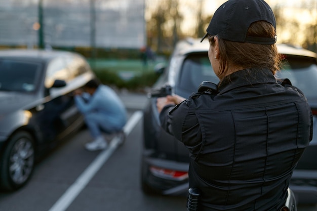 Policière pointant une arme sur un voleur de voiture