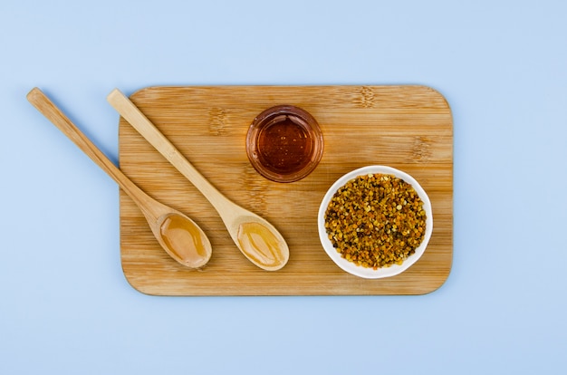 Photo pollen avec du miel et des cuillères en bois sur le placard