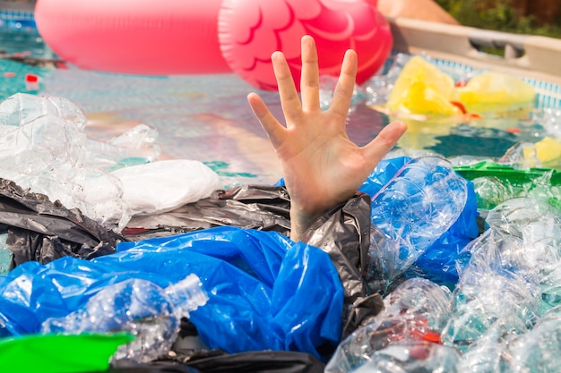 Pollution plastique et problème environnemental, main de l'homme dans la mer en plastique