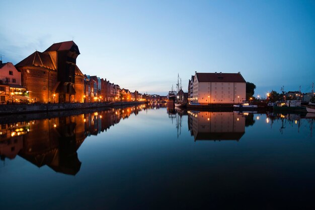 Pologne, Gdansk, rangée de maisons éclairées avec porte-grue à la banque Motlawa au crépuscule