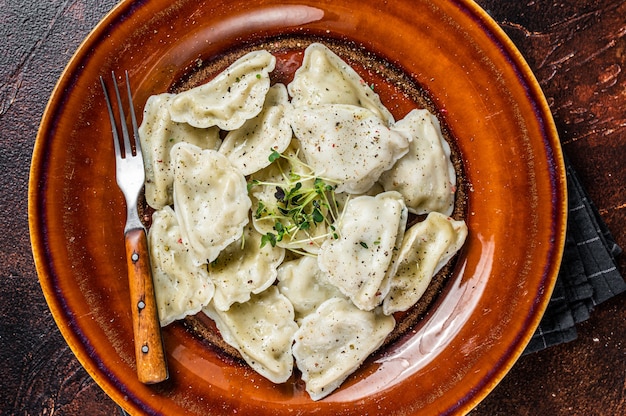 Polonais Pierogi Dumplings avec pomme de terre dans une assiette avec des herbes et du beurre