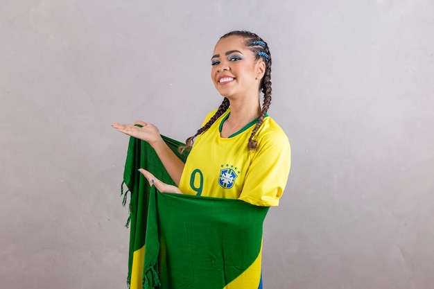 Pom-pom girl brésilienne sur fond jaune pointant vers le côté avec espace libre pour le texte