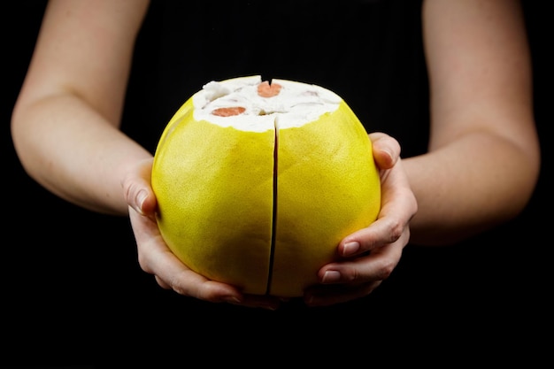 Photo pomelo, agrumes à la chair rouge douce et à la peau épaisse jaune sur noir