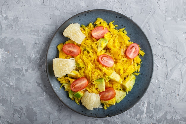 Pomelo frit avec tomates et avocat sur béton gris