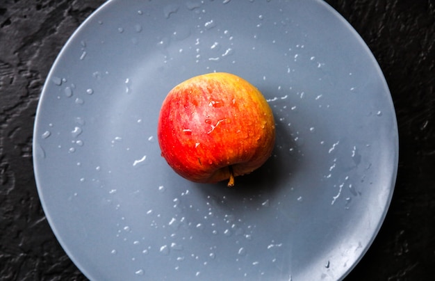 Une pomme allongée sur la plaque grise. Photo nature morte. Fond noir.