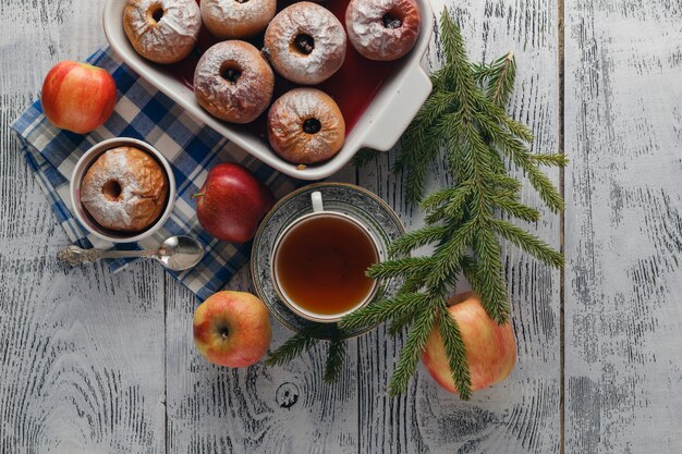 Pomme au four traditionnelle sur une table en bois, avec pomme et sucre en poudre. Près des branches d'arbres de Noël et des épices