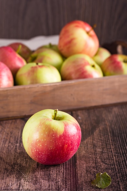 Pomme entière mûre sur le fond d'une boîte de fruits sur une table en bois Fruits de saison locaux Vertical