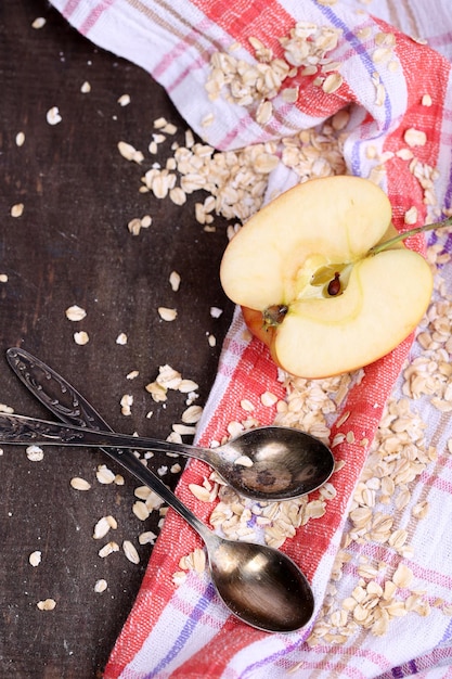 Pomme avec flocons d'avoine et cuillères vintage sur serviette sur fond de bois de couleur