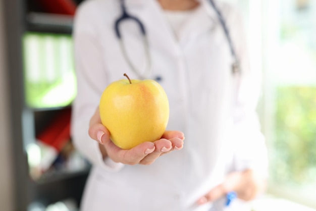 Pomme jaune mûre dans la main d'une femme nutritionniste concept d'alimentation saine