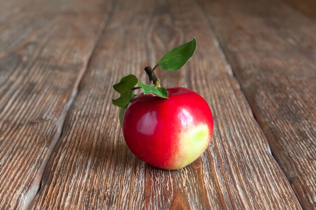 Une pomme mûre avec des feuilles sur une table en bois sombre