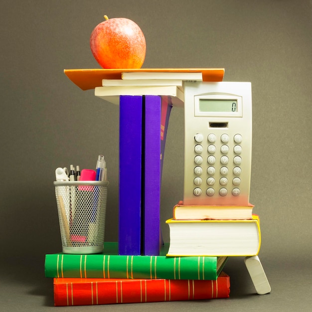 Photo pomme sur une pile de livres sur un fond gris