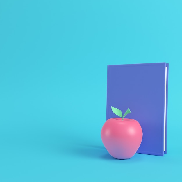 Pomme rose sur un livre sur fond bleu clair