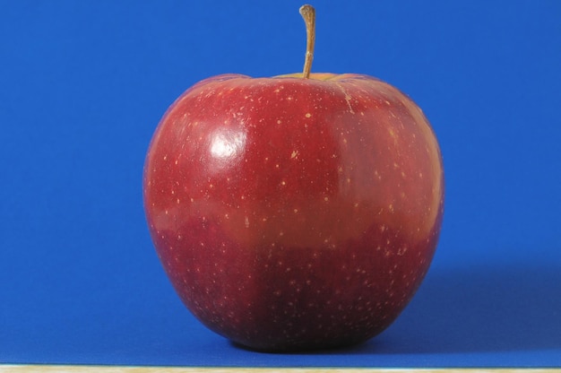 Une pomme rouge chaude juteuse sur un fond coloré