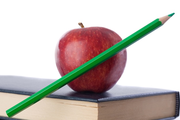 Une pomme rouge avec un crayon vert sur plusieurs livres sur fond blanc