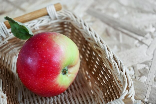 Pomme rouge dans un panier en osier sur un espace de copie de fond en bois