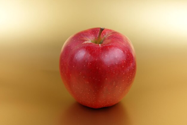 Pomme rouge entière sucrée juteuse sur fond doré Concept d'aliments sains Gros plan d'un fruit rouge