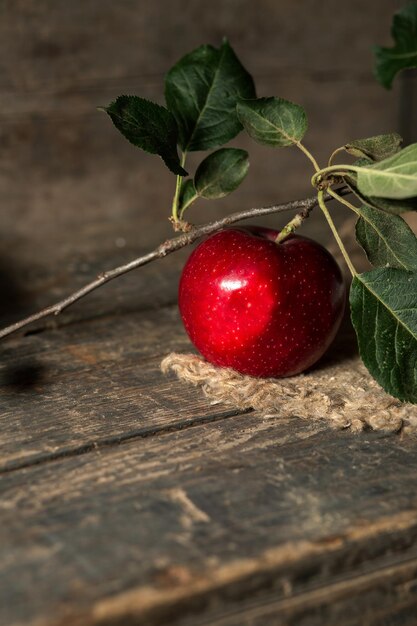 Pomme rouge avec des feuilles sur toile de jute sur des planches de bois