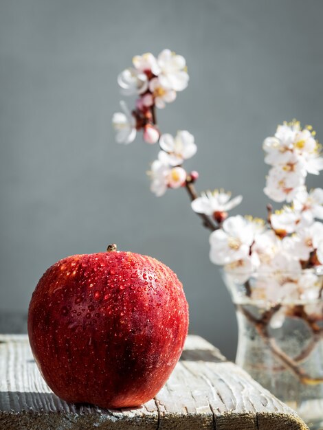 Pomme rouge fraîche avec des gouttes d'eau sur une table vintage en bois.