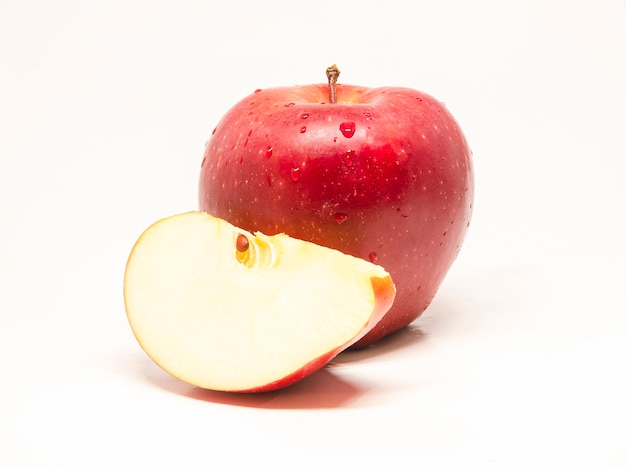 Pomme rouge fraîche et humide avec une tranche sur un blanc