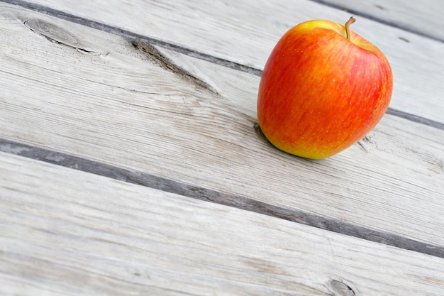 Une pomme rouge jaune sur une vieille surface en bois