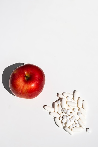 Pomme rouge et pilules ou capsules de vitamines sur l'espace de copie de tableau blanc Régime de bien-être ou supports pour le concept de santé