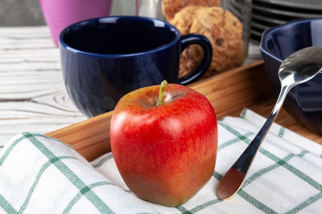 Pomme rouge avec une tasse de thé sur un plateau en bois