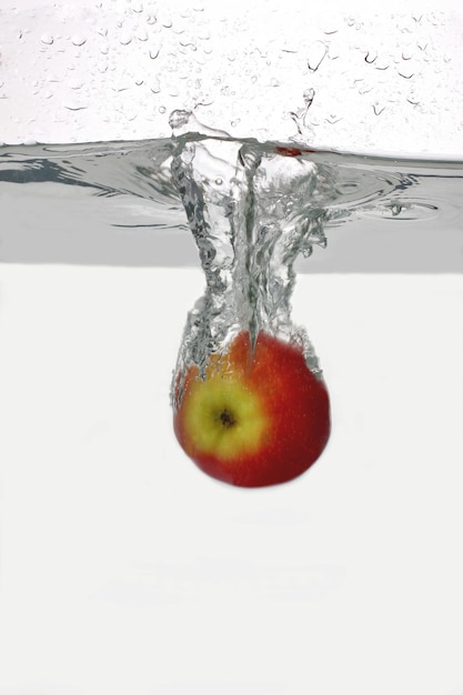 La pomme rouge tombe dans l'eau