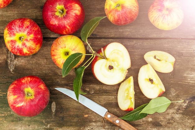 Pomme rouge en tranches et couteau sur une vieille table en bois