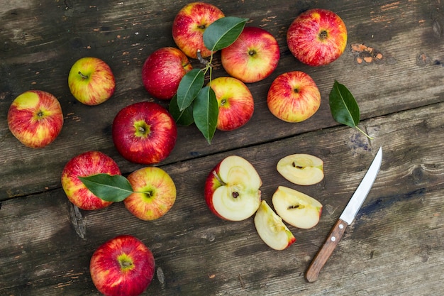 Pomme rouge en tranches et couteau sur une vieille table en bois