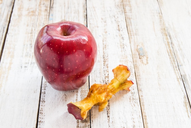 Pomme rouge et trognon de pomme sur un fond en bois blanc